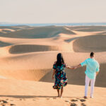 couple walking at the beach of Maspalomas Gran Canaria Spain, men and woman at the sand dunes desert of Maspalomas Spain Europe during vacation holidays in Europe