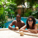 Happy young restful couple in sunglasses looking at camera with smiles while enjoying vacation at luxurious summer resort