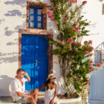 Men and women visit the whitewashed Greek village of Oia Santorini, a couple watching the sunrise in Santorini with blue domes and white churches