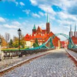 Cathedral Island in Wroclaw Poland green bridge with view on of St John the Baptist picturesque panorama medieval town blue sky and white cloud.