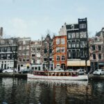 Charming Amsterdam canal scene with classic Dutch architecture and a boat cruising on the water.