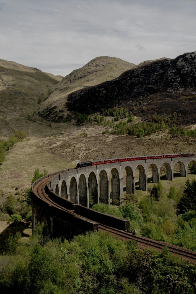 Train crosses the famous viaduct amidst scenic mountains and lush valley.