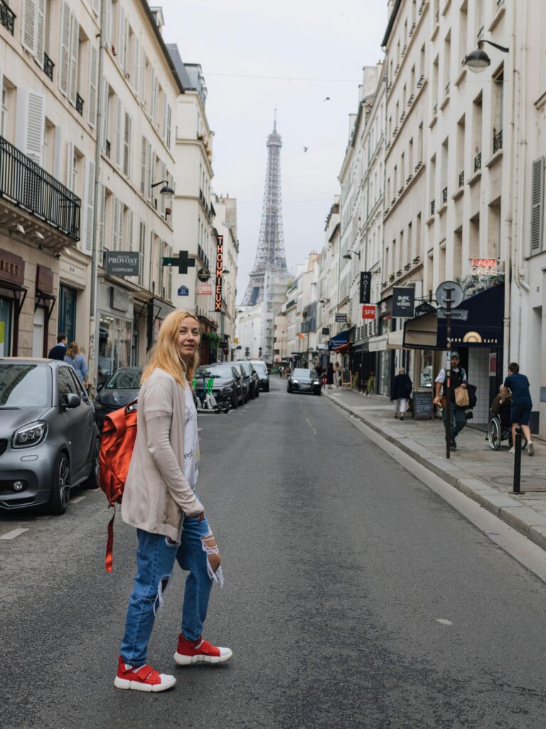 Scene of a woman strolling down a charming Paris street with the iconic Eiffel Tower in the background.