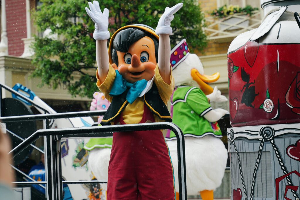Cheerful Pinocchio character waving during a lively Disneyland Paris parade.