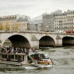 Tourists enjoy a picturesque ride on the Seine River with views of Parisian architecture and bridges.