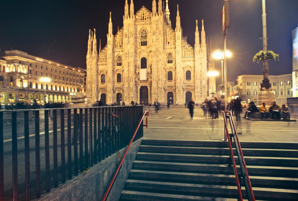 Captivating night scene of Milan Cathedral with lively city surroundings.