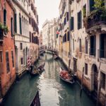 A vertical picture of gondolas on the grand channel between colorful buildings in Venice, Italy