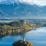 A vertical high angle shot of a building on a small island in Bled, Slovenia surrounded by high mountains