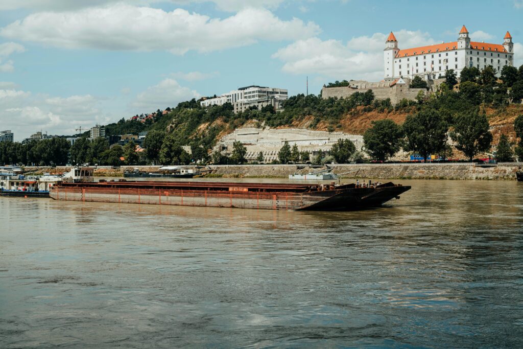 A picturesque barge cruising the Danube river with Bratislava Castle in the background.