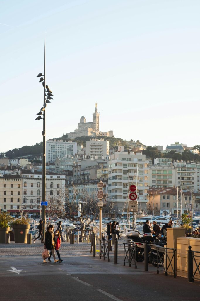 People strolling by the Vieux-Port with a view of Notre-Dame de la Garde in Marseille, France.