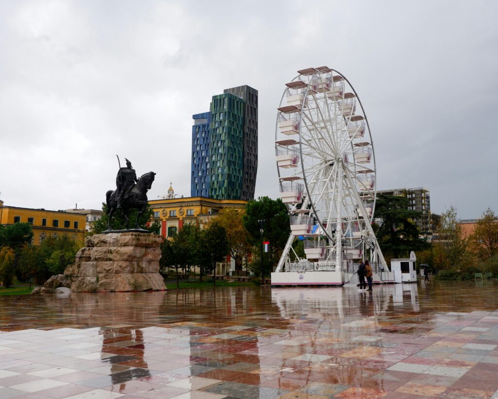 Explore the vibrant Skanderbeg Square in Tirana, featuring a ferris wheel and iconic statue.