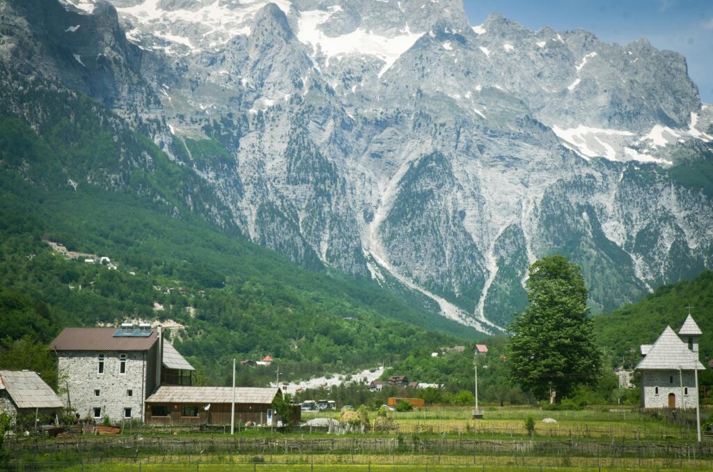 Scenic view of an alpine village nestled at the base of towering snow-capped mountains.