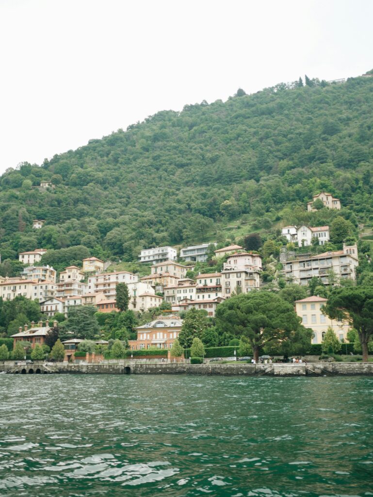 Charming hillside architecture along Lake Como, Italy, showcasing lush greenery and historic buildings.