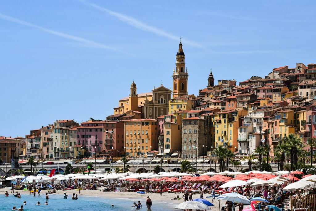 Lively beach scene with colorful buildings in Menton, Provence-Alpes-Côte d'Azur, France.