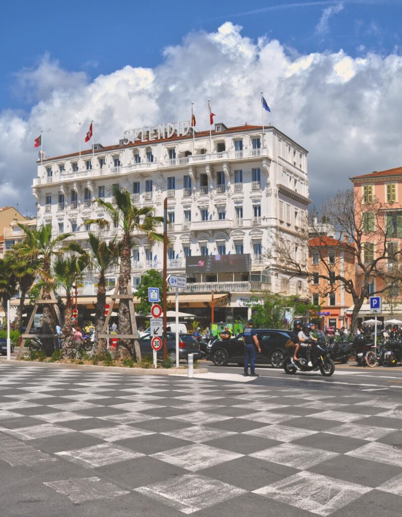 Charming street scene featuring Salendra Hotel in Cannes, France, with bustling activity and palm trees.