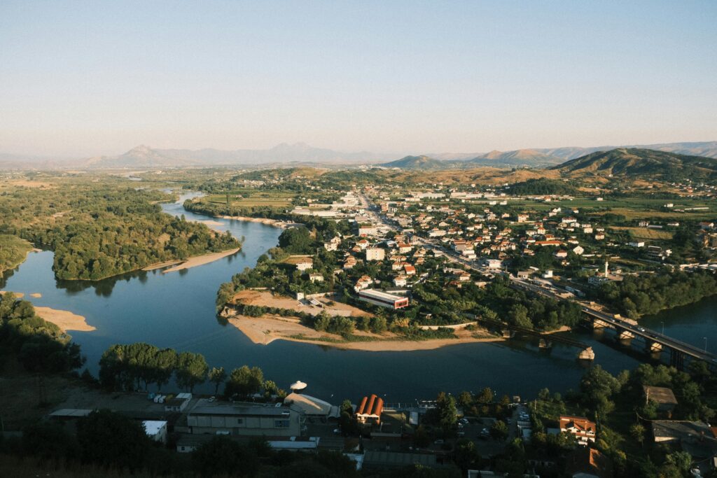 Beautiful aerial view of Shkodër city with meandering river and surrounding mountains.