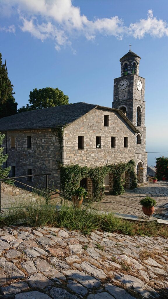 Beautiful stone church with tower in Agios Georgios, Greece on a sunny summer day.