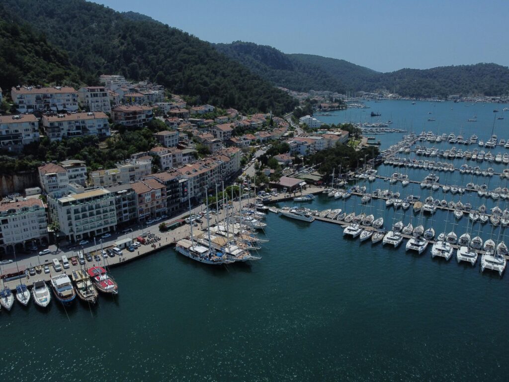 Captivating aerial shot of Turkish marina with yachts and scenic coastal landscape.
