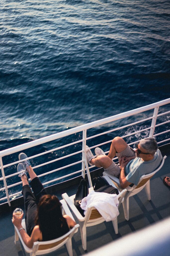 Couple relaxing on a cruise ship deck, enjoying the serene ocean view on a sunny day.