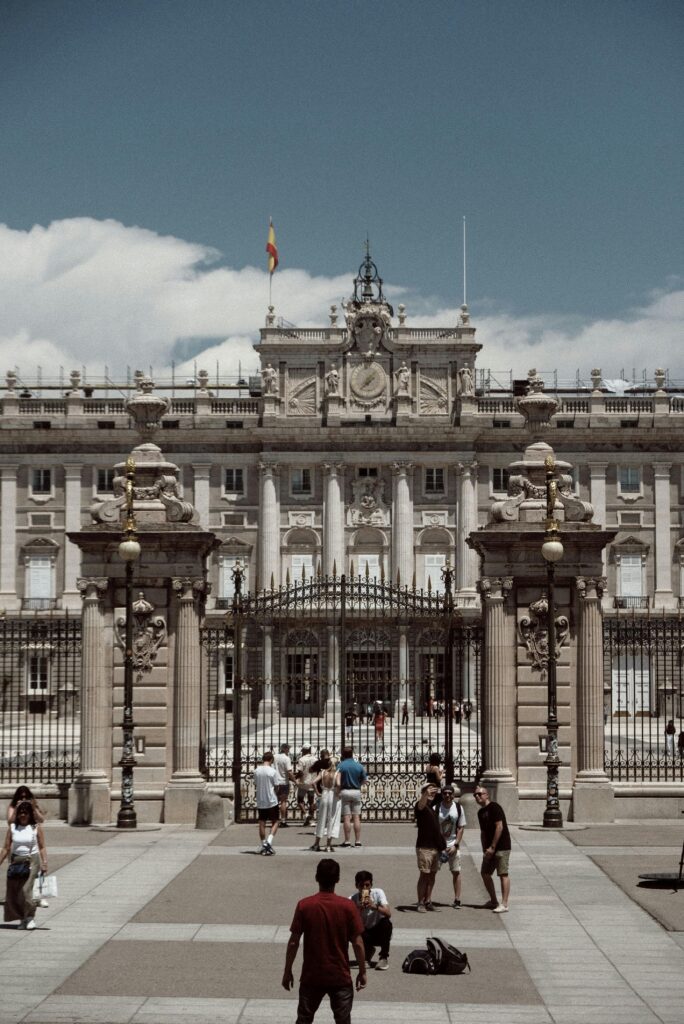 The historic Royal Palace of Madrid with tourists exploring the iconic landmark during summer.