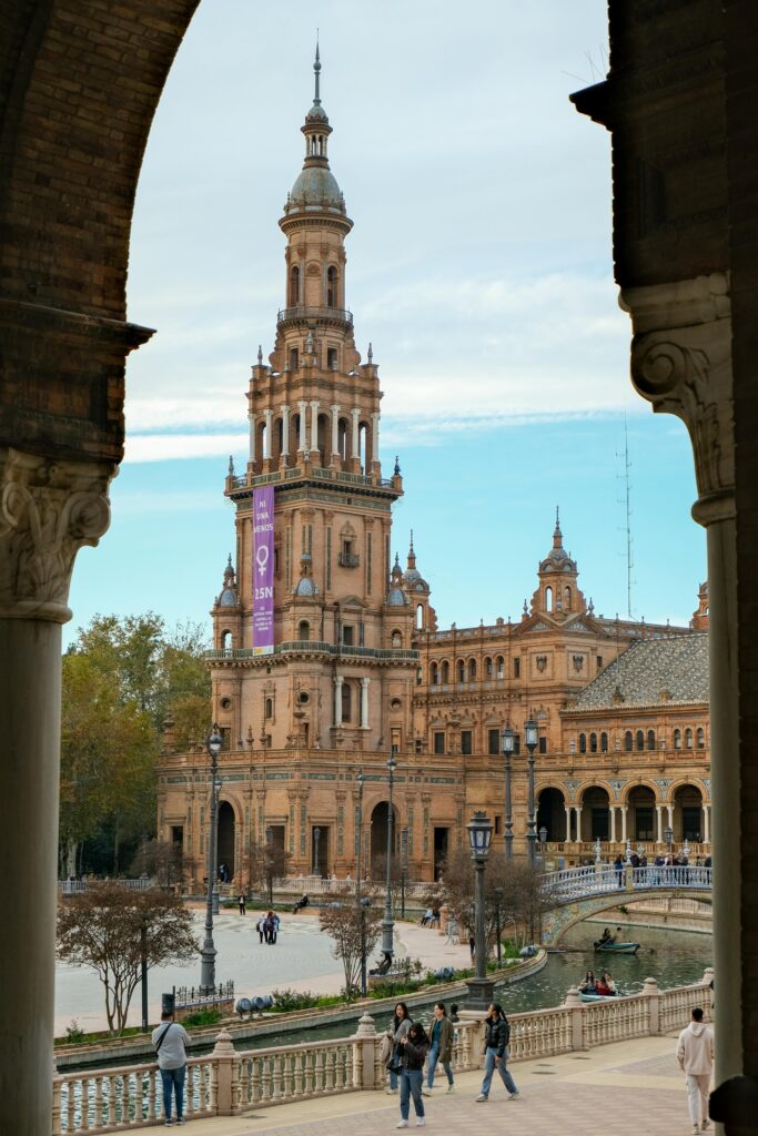 A picturesque view of Plaza de España in Seville through an archway, showcasing its majestic architecture.