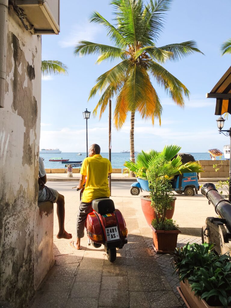 A vibrant scene of a man on a scooter by the beach in Zanzibar, Tanzania.