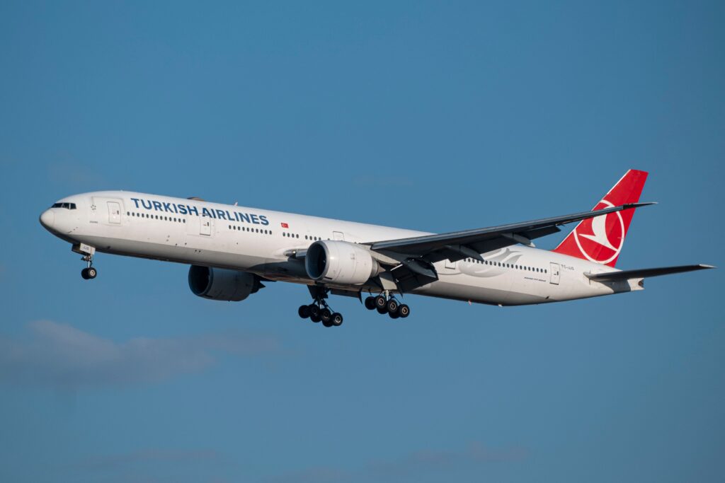 Turkish Airlines Boeing 777 aircraft flying in clear blue sky.