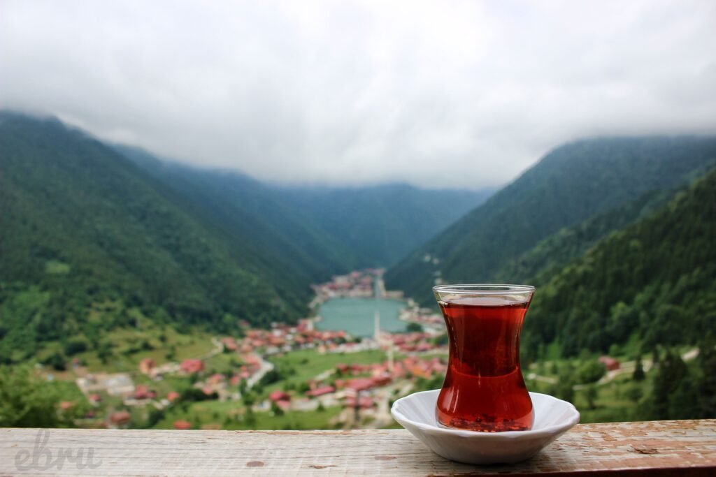 Enjoy a serene view of traditional Turkish tea with a misty mountain backdrop, creating a peaceful outdoor atmosphere.