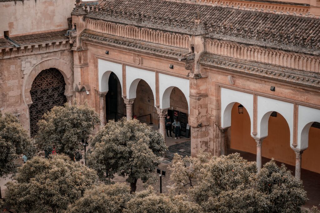 Aerial view of the historic Mosque-Cathedral of Córdoba with its iconic arches and surrounding trees.