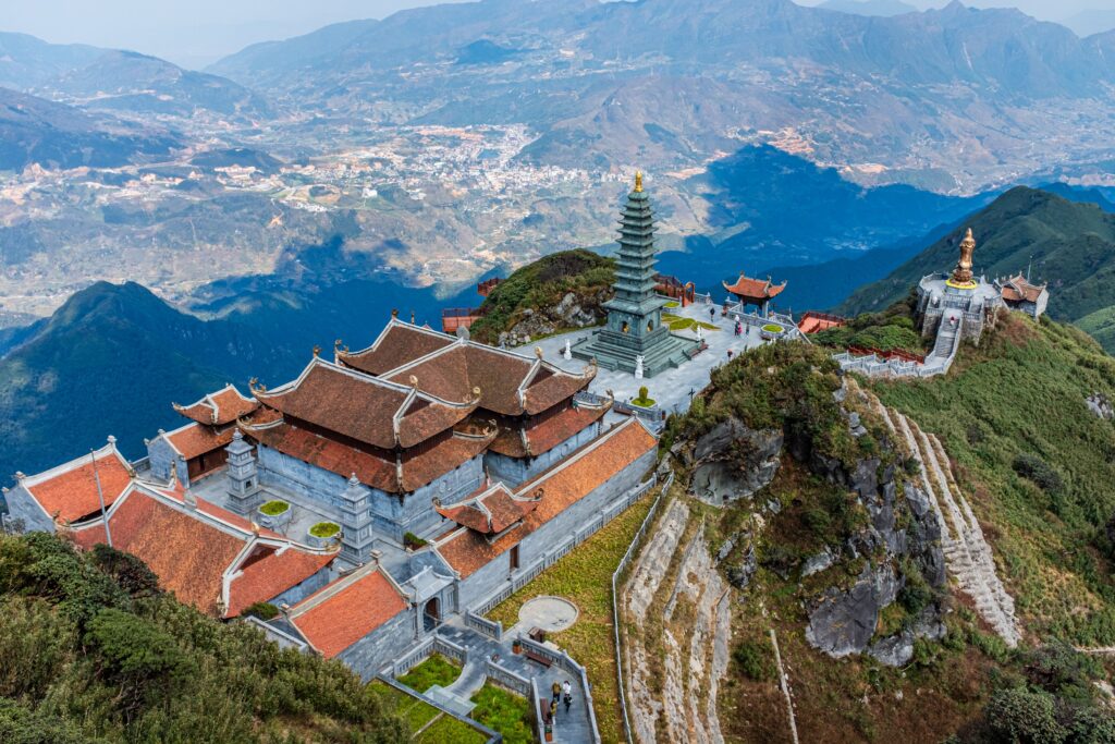 Scenic aerial view of Fansipan Pagoda Complex surrounded by mountains in Vietnam. Captures architectural elegance.