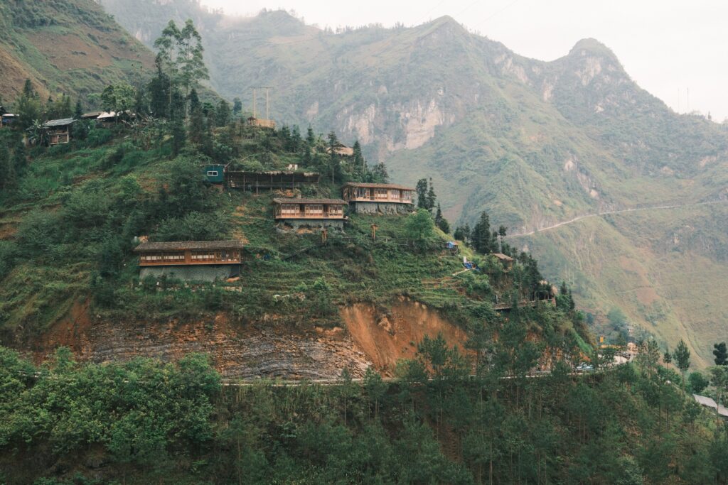 Breathtaking view of houses on a misty mountain slope, surrounded by lush greenery.