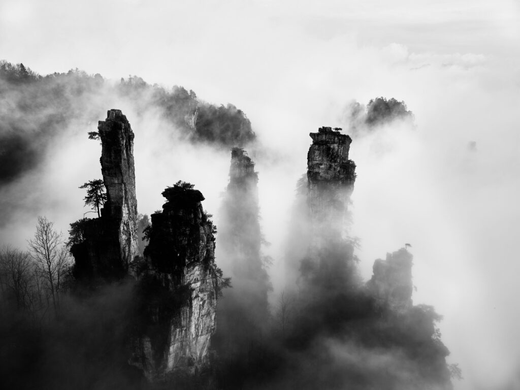 Dramatic black and white image of Zhangjiajie peaks enveloped in mist.